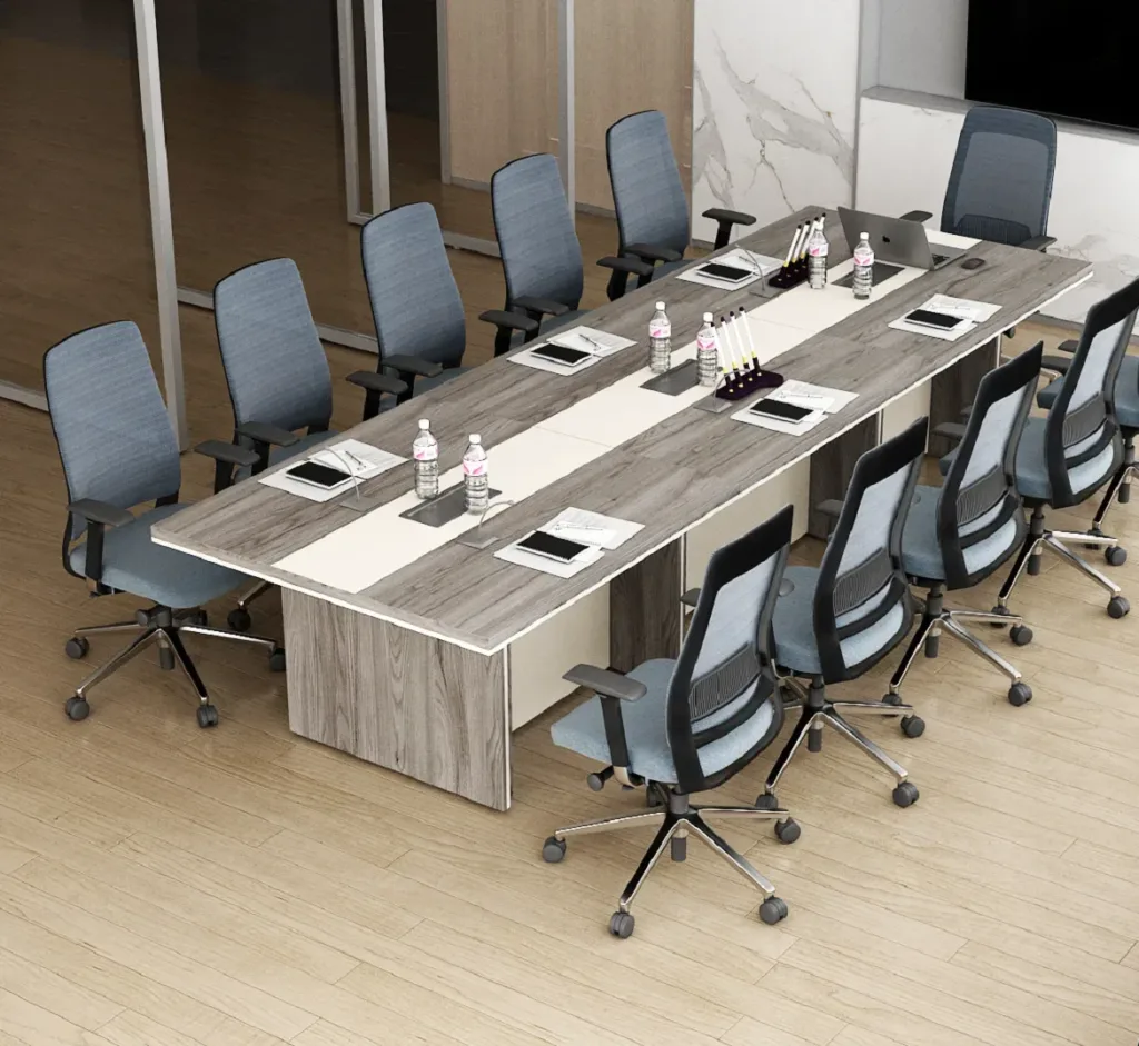 A modern conference room features a long wooden conference table for office, twelve gray chairs, bottled water, notepads, and pens at each seat, set on a light wood floor with glass walls in the background.